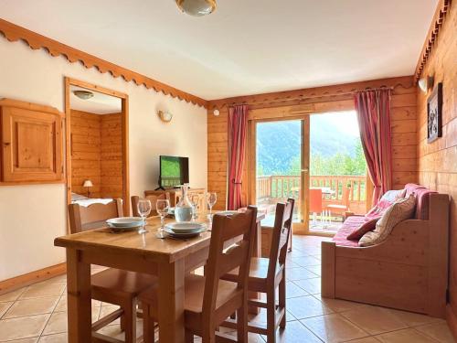 une salle à manger avec une table en bois, des chaises et une télévision dans l'établissement L’Arolle Spa, Calme & Vue Montagne, à Champagny-en-Vanoise