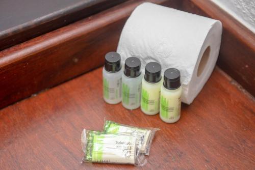 three bottles of lotion next to a roll of toilet paper at Pousada Vila Ravello in Búzios