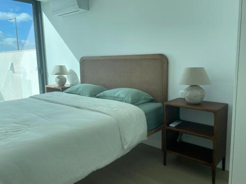 a bed with blue pillows and a night stand with a lamp at Lux Hiato's Villa in Luz de Tavira