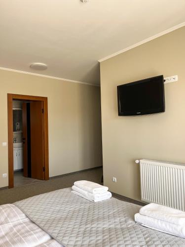 a bedroom with two beds and a flat screen tv on the wall at Ресторан-Готель Шеркерт in Berehove
