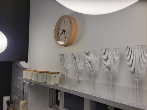 a row of wine glasses on a shelf with a clock at Gwangalli Yellow Door in Busan