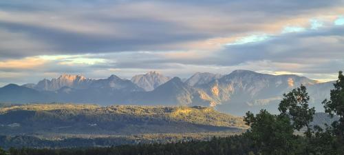 a view of a mountain range with clouds and trees at ZAUBERBERG Apartements in Schwarzendorf