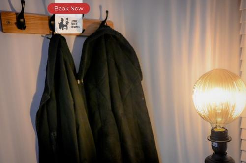 a green robe hanging on a rack next to a lamp at 2 Bedroom Apartment By Littlepiggyrentals Short Lets & Serviced Accommodation Stansted Mountfitchet Near Stansted Airport in Stansted Mountfitchet