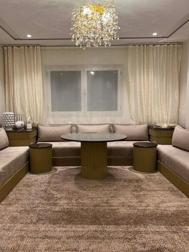 a living room with a table and couches and a chandelier at Nara luxe 3 Berkane in Berkawe