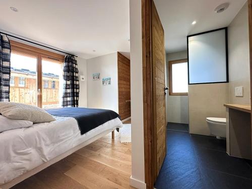 une chambre avec un lit et une salle de bain avec une fenêtre dans l'établissement Le Malatray Chalet spacieux vue montagne, à Champagny-en-Vanoise