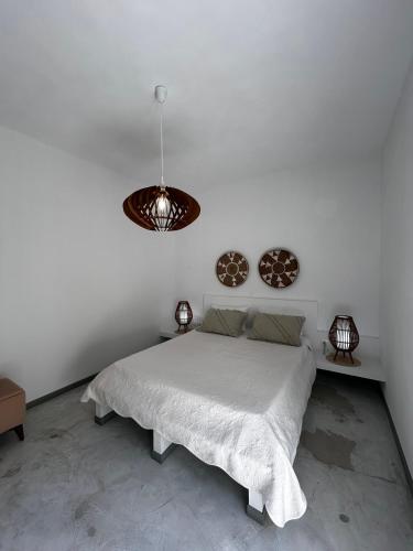 a white bedroom with a bed and a pendant light at white house apollon naxos in Apollon