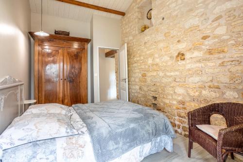 a bedroom with a bed and a stone wall at le chai de la lumineuse in Saint-Pierre-dʼOléron