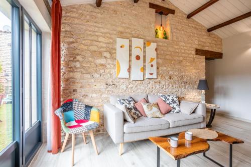 a living room with a couch and a brick wall at le chai de la lumineuse in Saint-Pierre-dʼOléron