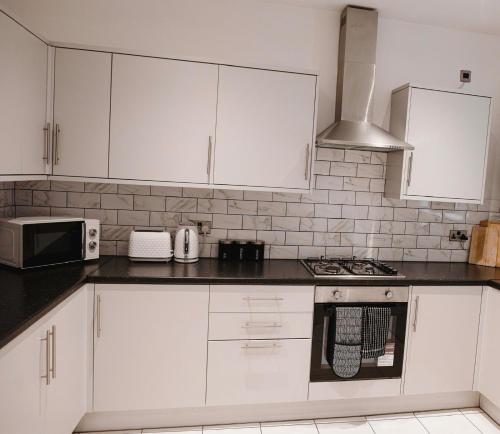 a kitchen with white cabinets and a stove top oven at Contemporary Private Bedroom Retreat in Sheffield