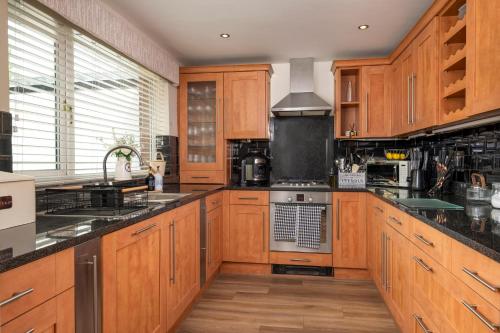 a kitchen with wooden cabinets and a stove top oven at 4-Bed House sleeps 8 Groups & Work Stays in Penrith