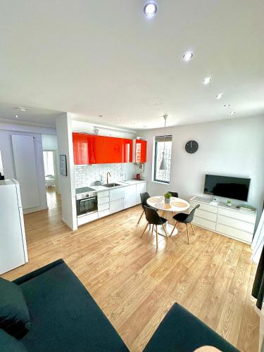 a living room with a table and a kitchen with red cabinets at Summerland Seaview Apartments in Mamaia