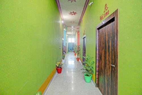 a hallway with green walls and a door and plants at Hotel O Dwarka in Alīgarh