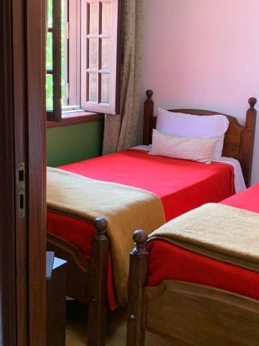 a bedroom with two beds with red sheets and a window at Casa Augusta - QUINTA in Penafiel