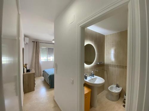 ein Badezimmer mit Waschbecken, Bett und Spiegel in der Unterkunft Apartamento La Laguna in Chipiona