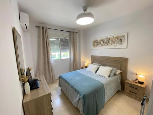 Schlafzimmer mit einem Bett mit blauer Tagesdecke in der Unterkunft Apartamento La Laguna in Chipiona