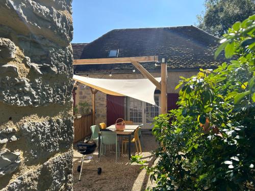 a patio with a table and chairs in front of a house at Le Domaine de la Claire Fontaine Gîtes -chambres d'hôtes in Montvalent