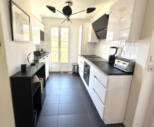 une cuisine avec des armoires blanches et des comptoirs noirs dans l'établissement ApartHotel Riviera - Balcon du Serrurier - Old Town - Promenade des Anglais, à Nice