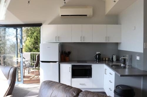 a kitchen with white cabinets and a couch at The Tamar Ridge Lookout 2BR 2Bath Suite in Grindelwald
