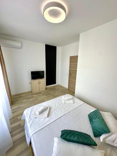 a bedroom with a white bed with green pillows at Summerland Seaview Apartments in Mamaia