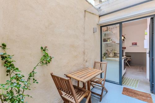 d'une terrasse avec une table en bois et 2 chaises. dans l'établissement Evangile - Cosy studio avec petite cour privee, à Paris
