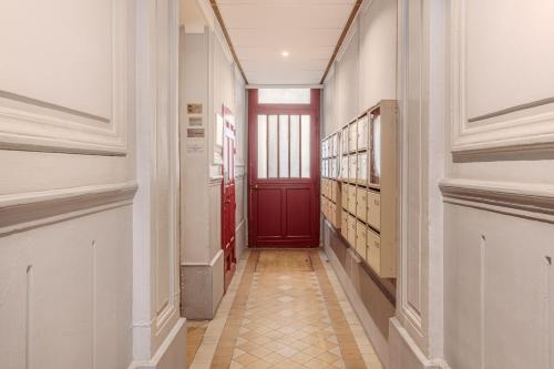 un couloir avec une porte rouge dans un bâtiment dans l'établissement Evangile - Cosy studio avec petite cour privee, à Paris