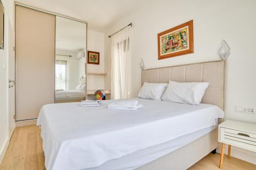 a bedroom with a large white bed and a mirror at Twin Towers LT Luxury in Becici