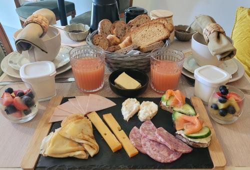 a table with a plate of food with bread and cheese at Agapanthe & Salicorne - Maison d'hôtes, Chambres d'hôtes- in Pluduno