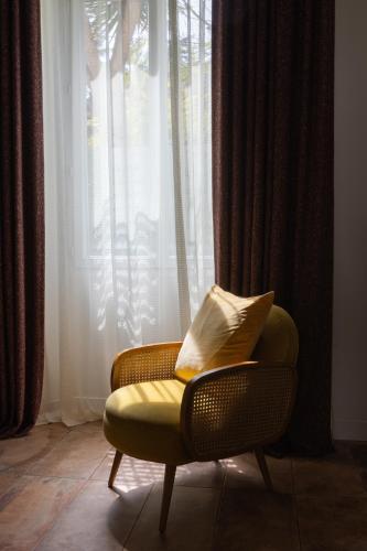 a yellow chair sitting in front of a window at Hotel Verlaine in Cannes