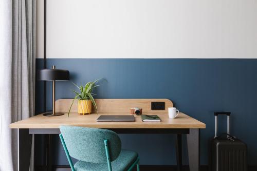 a wooden desk with a laptop and a chair at voco Belfast by IHG in Belfast