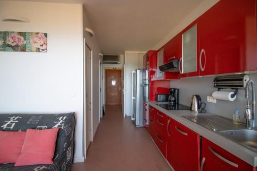 une cuisine avec des armoires rouges et un comptoir dans l'établissement Résidence Aria Marina Plage, à Ajaccio