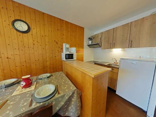 une cuisine avec une table et une horloge au mur dans l'établissement Studio cosy 4 pers au Grand-Bornand, près des pistes, animaux admis - FR-1-241-37, au Grand-Bornand