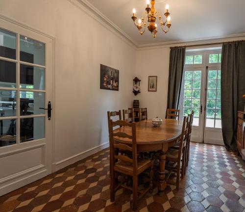 une salle à manger avec une table, des chaises et un lustre dans l'établissement Le Moulin, à Romilly-sur-Aigre