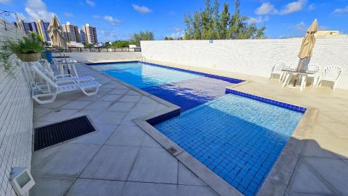 a swimming pool with chairs and a table next to a building at Luxuoso apê recém reformado na Farolândia in Atalaia Velha