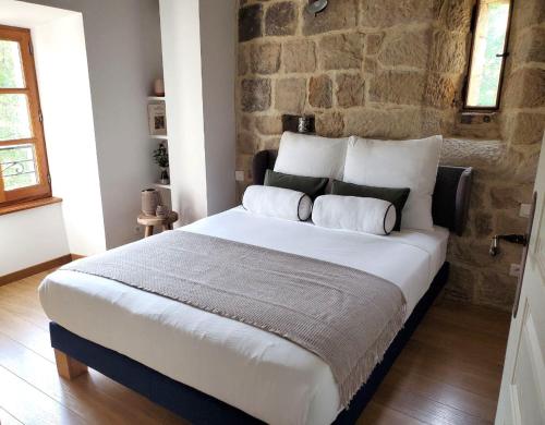 - un grand lit dans une chambre dotée d'un mur en pierre dans l'établissement Charmante Maison en Pierres Sud Ardèche, à Saint-André-Lachamp