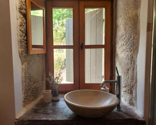 La salle de bains est pourvue d'un lavabo à bol en face d'une fenêtre. dans l'établissement Charmante Maison en Pierres Sud Ardèche, à Saint-André-Lachamp