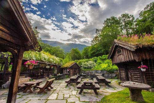 a patio with picnic tables and benches in a garden at Ullensvang Gjesteheim in Lofthus