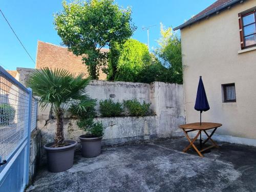 un patio avec une table et un parasol et une clôture dans l'établissement Maison Vigneronne Typique, à Ménétréol-sous-Sancerre