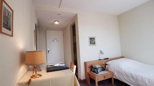 a bedroom with a bed and a table with a lamp at Seiler au Lac in Bönigen