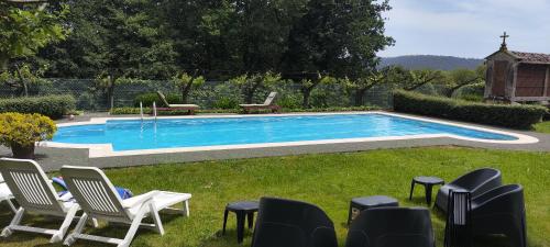 a swimming pool in a yard with chairs around it at O Retiro de Bernardo in Teo