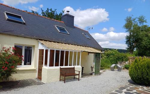 una casa con una panchina davanti di Keriven Cottage a Keriven