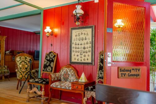 a room with red walls with chairs and a table at Ullensvang Gjesteheim in Lofthus