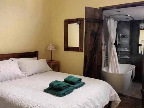 a bedroom with a bed with a bath tub and green towels at Room with luxury private bathroom and independent entrance near Tube in London