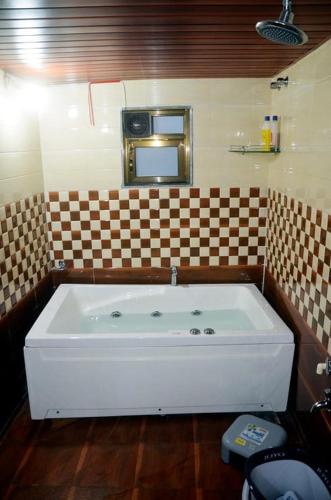 a large white tub in a bathroom with a mirror at Appa's Rain Hill Villa in Thane