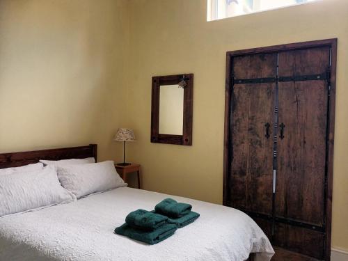 a bedroom with a bed with green towels on it at Room with luxury private bathroom & independent entrance near Tube in London