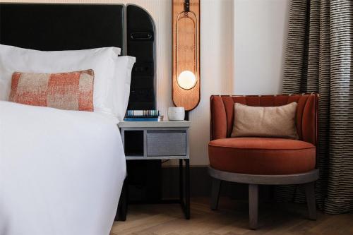 a bedroom with a bed and a chair and a side table at Hart Shoreditch Hotel London, Curio Collection by Hilton in London