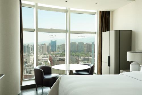 a hotel room with a bed and a large window at Conrad Urumqi in Ürümqi