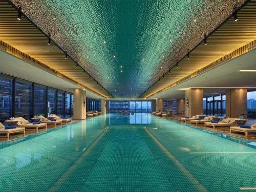 a swimming pool with chairs in a building at Hilton Jiashan in Jiaxing