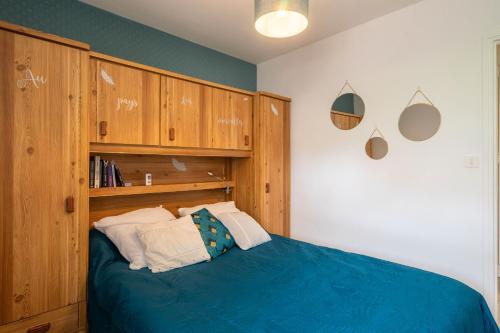 - une chambre avec un lit bleu et des placards en bois dans l'établissement L'Echappée Royannaise, à Royan