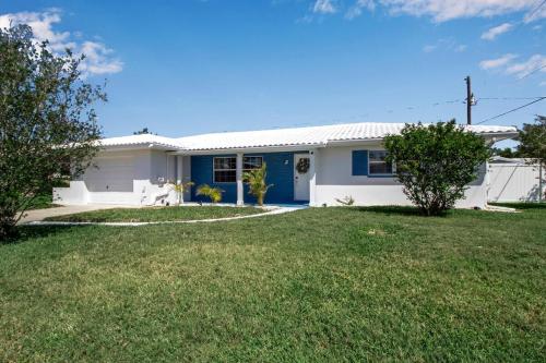 a white and blue house with a grass yard at Madeira Beach Family & Pet Friendly Luxury Getaway in Seminole