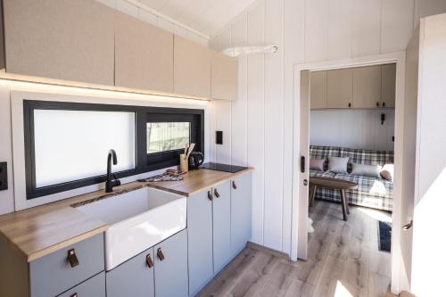 a kitchen with white cabinets and a sink and a window at ARIETES MARMONT Tiny Houses in Štrbské Pleso